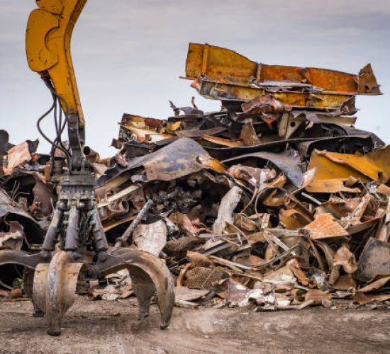 Large tracked excavator working a steel pile at a metal recycle yard, France
